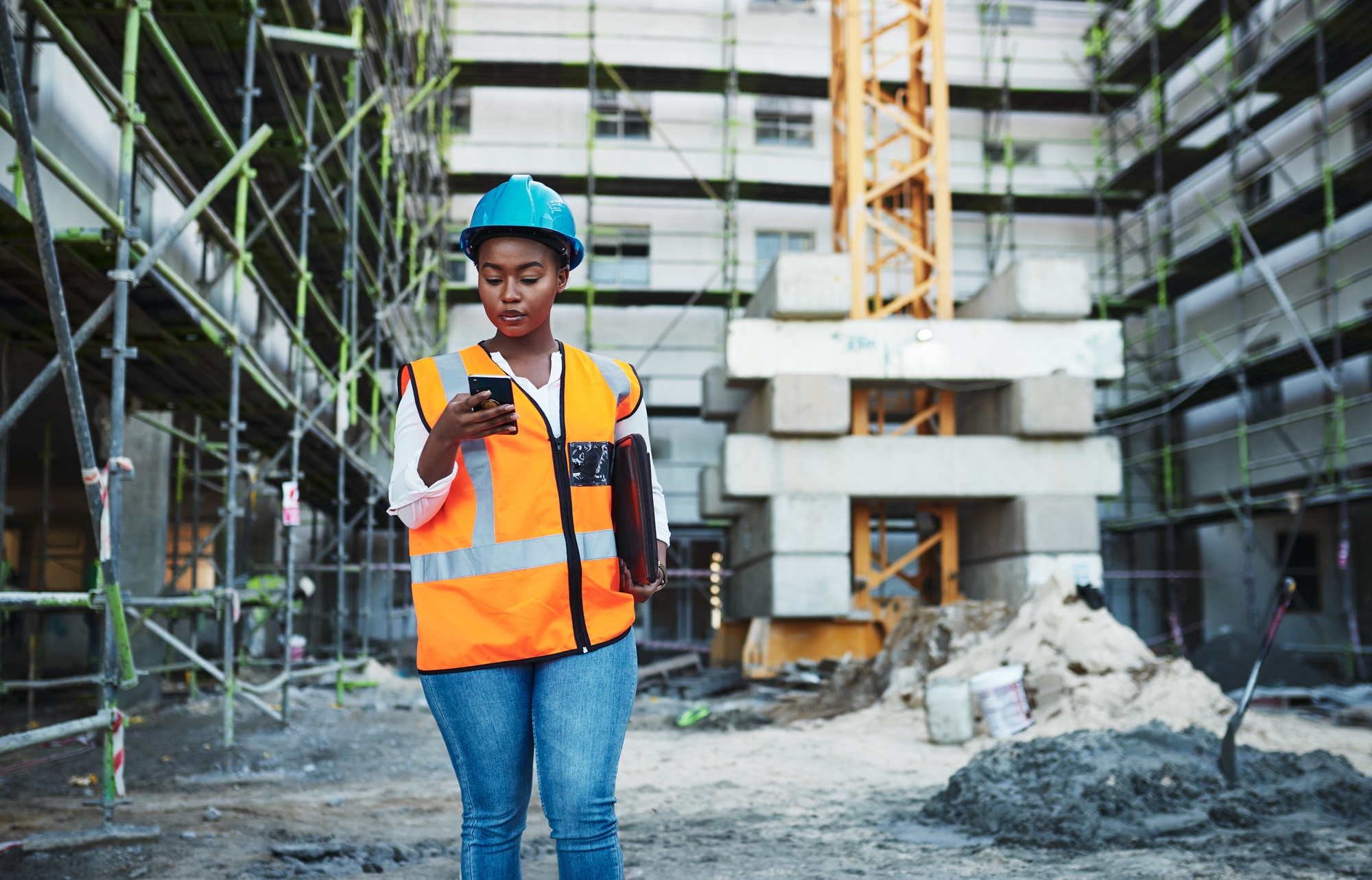 Shot of a young woman using a smartphone while working at a construction site